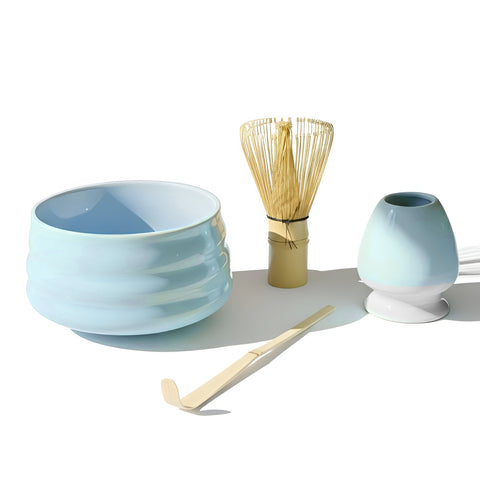 Gewurzladen Nafels Hellblaue Matcha-Schale, Bambusbesen und Löffel auf einem weißen Hintergrund.