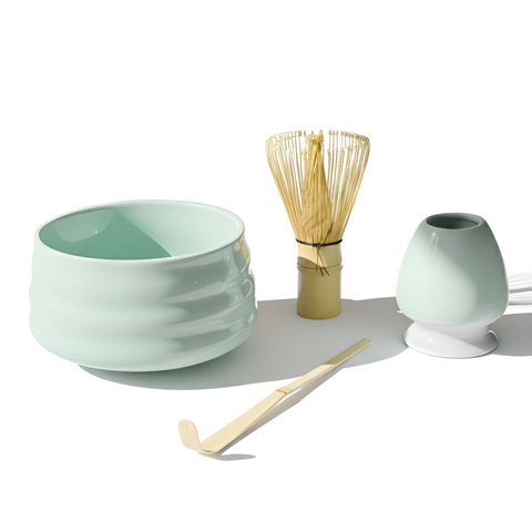 Gewurzladen Nafels Minzgrüne Matcha-Schale, Bambusbesen und Löffel auf einem weißen Hintergrund.