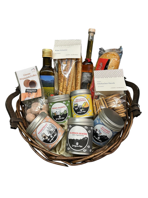 Gewurzladen Nafels Weidenkorb gefüllt mit Gewürzen, Ölen, Käse-Grissini und Glarnermagentrüffel Schokoladen.